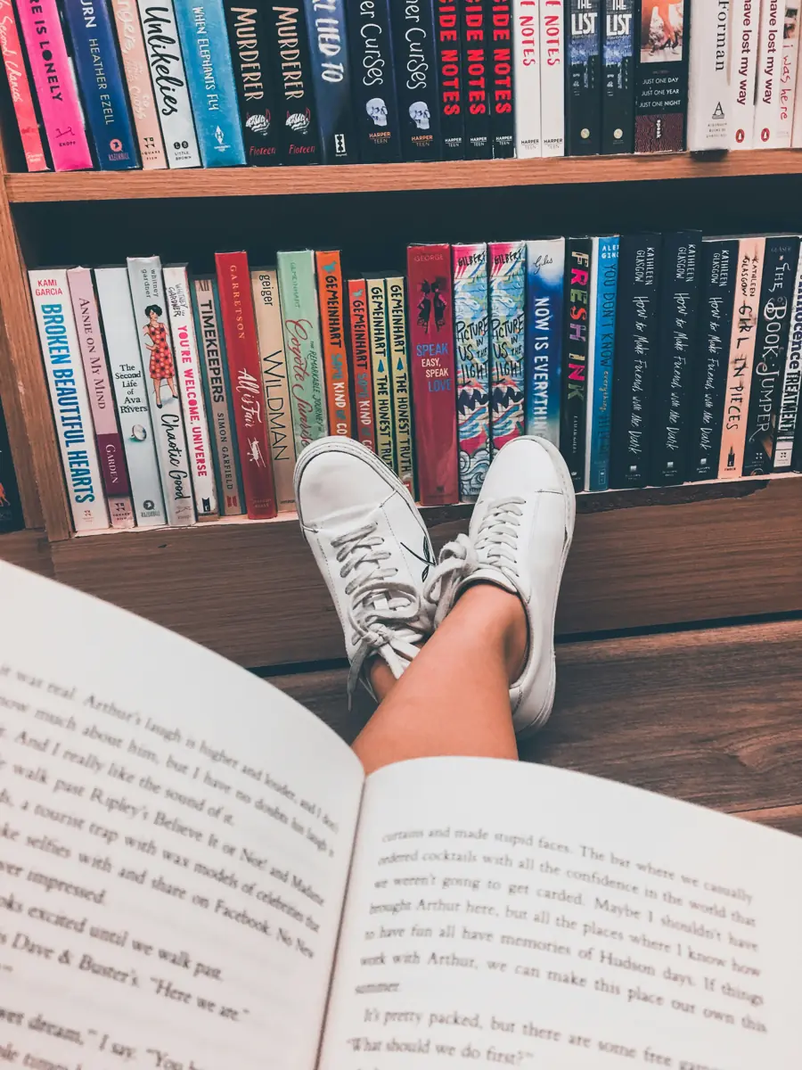 Bücherregal und eine Person, die mit einem Buch entspannt