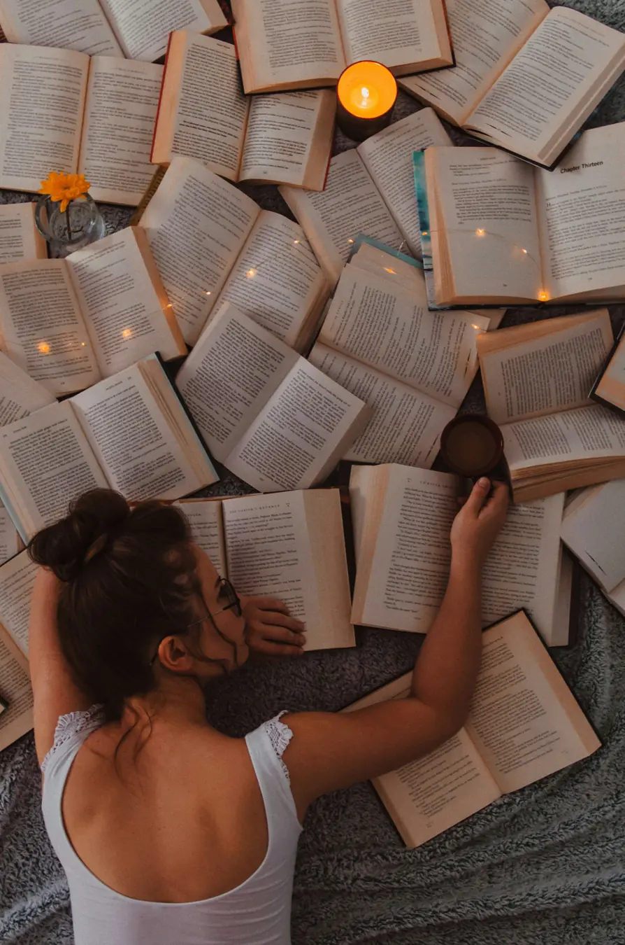 Leserin umgeben von aufgeschlagenen Büchern